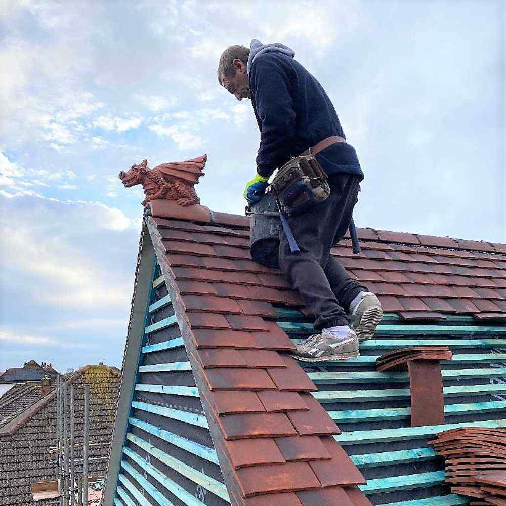 Roofers installing a dragon finial